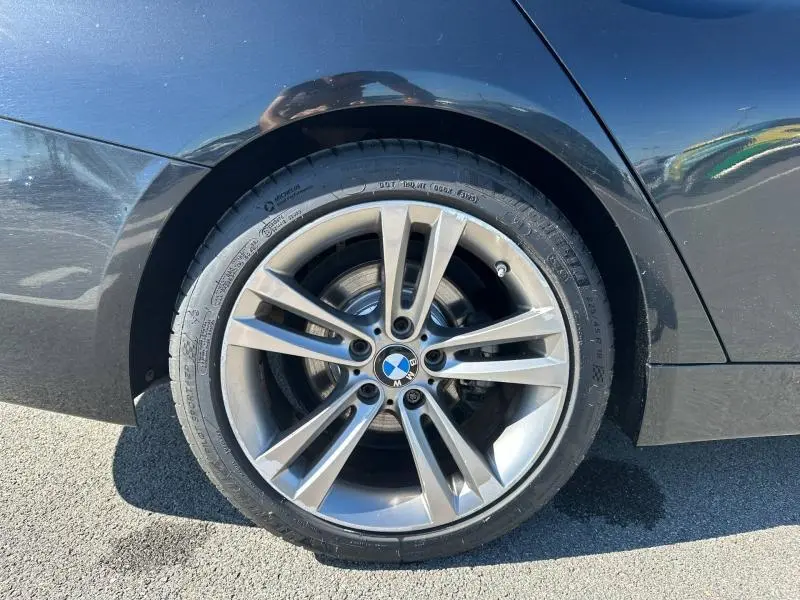 Gros plan sur la roue arrière droite d’une BMW Série 4 Gran Coupe noire avec jante alliage à 5 doubles branches.