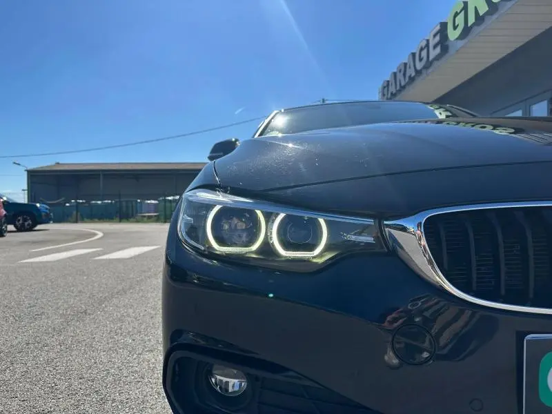 Gros plan sur l'avant gauche d'une BMW Série 4 Gran Coupe noire avec phares LED allumés et calandre chromée.