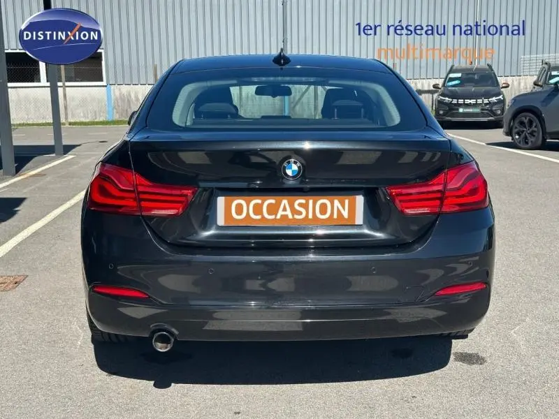 Vue arrière d'une BMW Série 4 Gran Coupé noire de 2018 avec feux LED et échappement visible côté gauche.