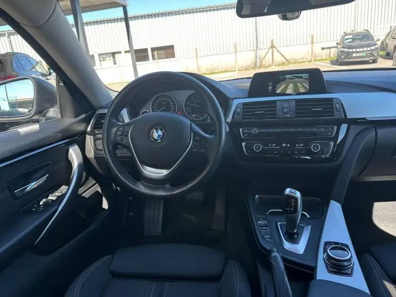Vue intérieure avant de la BMW Série 4 Gran Coupe noire, avec volant multifonction et écran central affichant la caméra de recul.