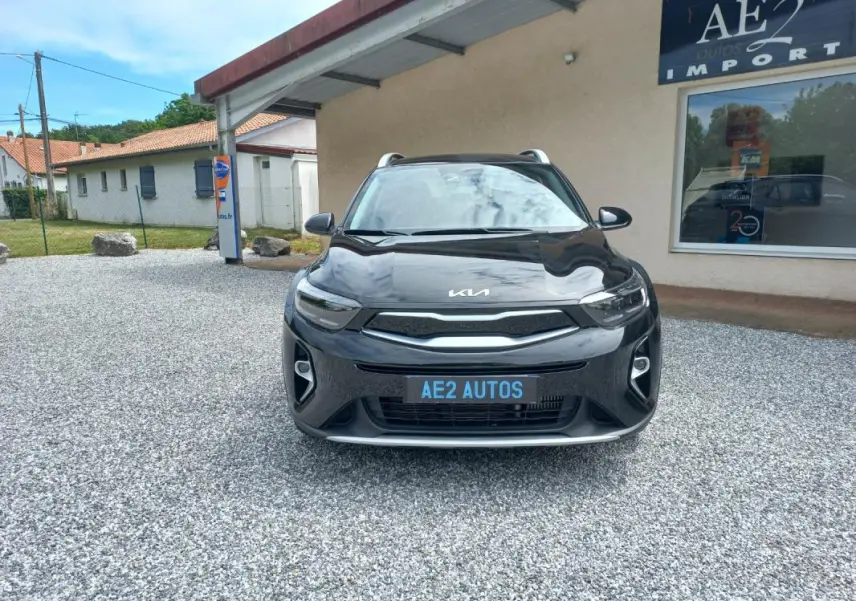 Vue de face d'un KIA STONIC noir 2025, avec calandre moderne et phares LED, stationné devant un bâtiment AE2 Autos.