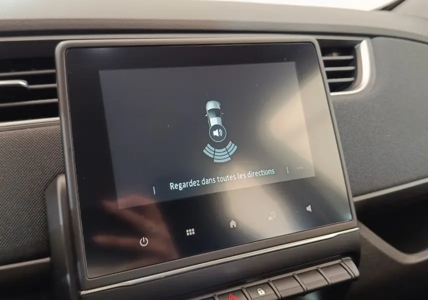 Écran tactile central de la Renault ZOE blanche 2021 affichant l'aide au stationnement intérieur.