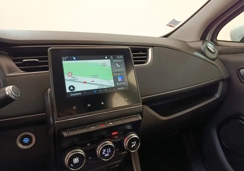 Vue intérieure côté passager du tableau de bord noir de la Renault ZOE 2021 avec écran tactile de navigation allumé.