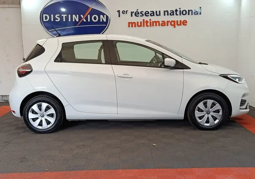 Profil droit d'une Renault ZOE Business Rev R110 blanche de 2021, avec jantes alliage et feux LED visibles.