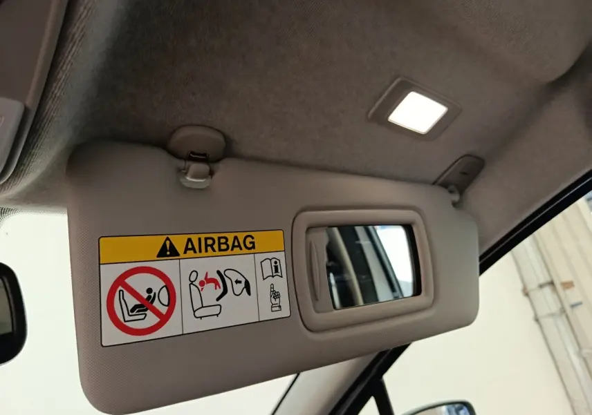 Détail du pare-soleil côté conducteur avec miroir et avertissement airbag dans une Renault ZOE blanche 2021.