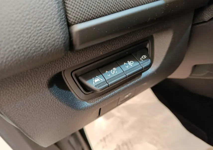Gros plan sur les boutons de réglages d'assistance et éclairage dans l'habitacle de la Renault ZOE blanche 2021.