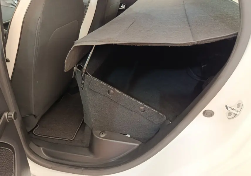 Vue intérieure côté arrière droit de la Renault ZOE blanche 2021, montrant le coffre partiellement ouvert et la banquette arrière.