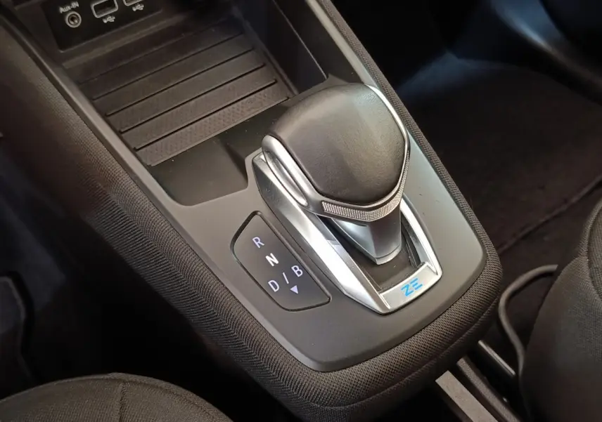Gros plan sur la commande de boîte automatique noire avec logo ZE dans l’habitacle de la Renault ZOE blanche.