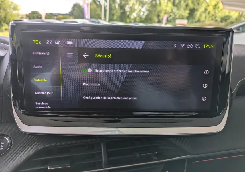 Écran tactile central de la Peugeot 208 Hybrid 145 GT affichant le menu sécurité, intérieur noir avec surpiqûres vertes.