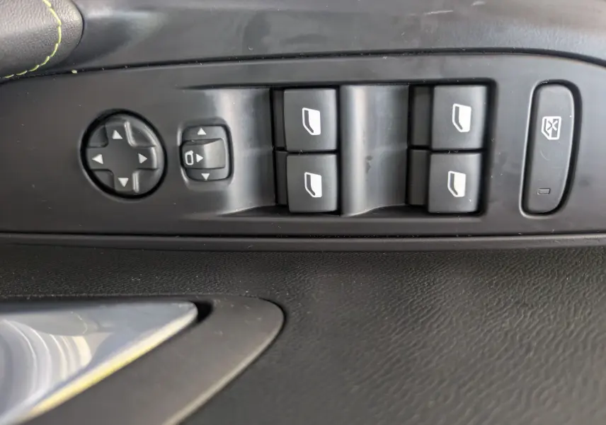 Gros plan sur les commandes de lève-vitres et réglage des rétroviseurs côté conducteur de la Peugeot 208 Hybrid 145 GT.