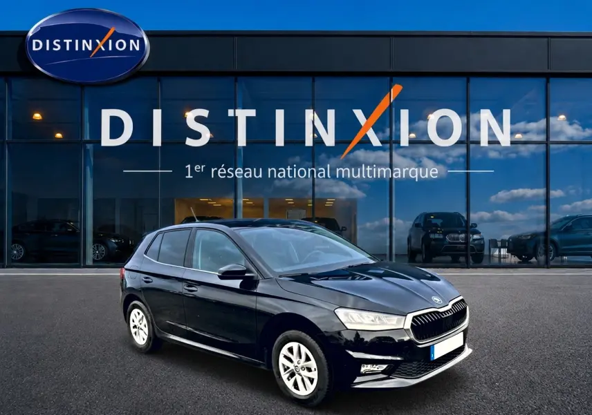 Vue 3/4 avant droite d'une Skoda Fabia noire garée devant une vitrine avec logo Distinxion.