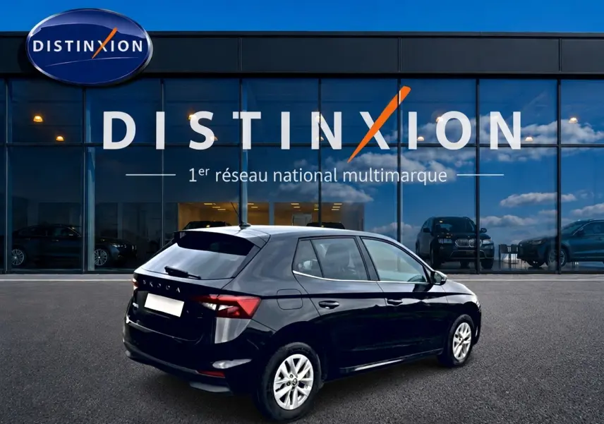 Vue 3/4 arrière droite d'une Skoda Fabia noire 2025 stationnée devant une vitrine Distinxion, jantes alu visibles.