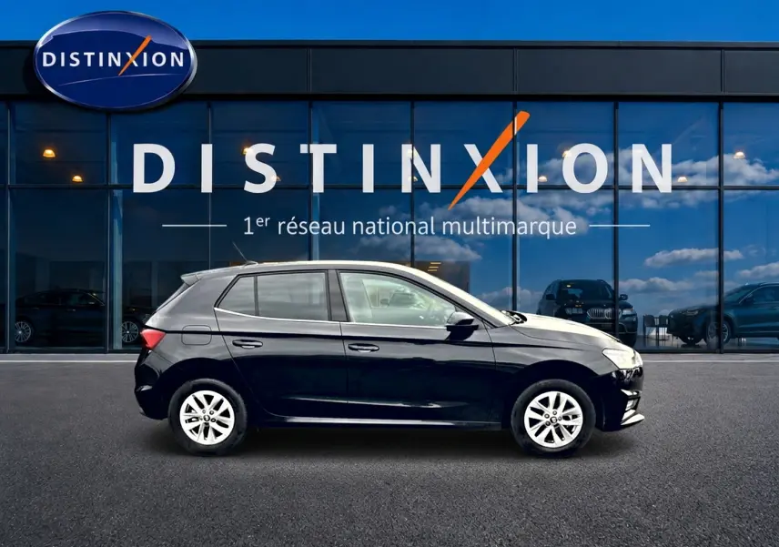 Profil côté gauche d'une Skoda Fabia noire 2025 garée devant une vitrine avec logo Distinxion.