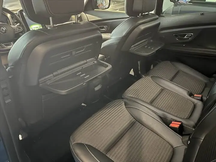 Vue intérieure arrière droite du Renault Scenic IV DCI 160 Energy avec sièges noirs et tablettes pliantes intégrées aux dossiers.