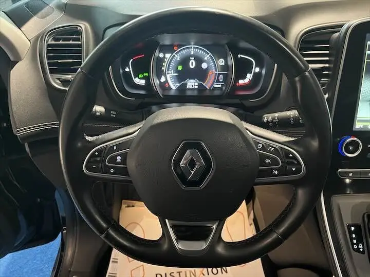 Vue rapprochée du volant noir de Renault Scenic IV avec tableau de bord numérique et commandes intégrées visibles.
