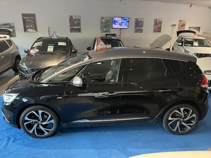 Renault Scénic IV noir étoile métal avec toit gris, vue profil côté gauche en intérieur de showroom.