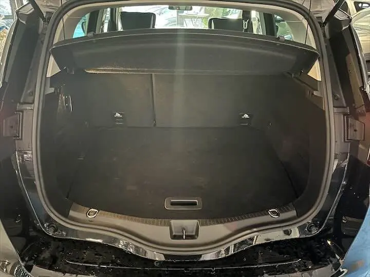 Coffre ouvert vu de l'arrière d'un Renault Scenic IV noir étoile métal avec intérieur sombre et cache-bagages.