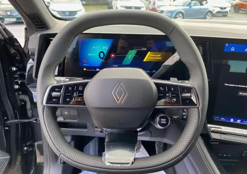 Vue intérieure du volant cuir perforé et tableau de bord numérique du Renault Austral noir étoilé 2025 E-Tech Hybrid.
