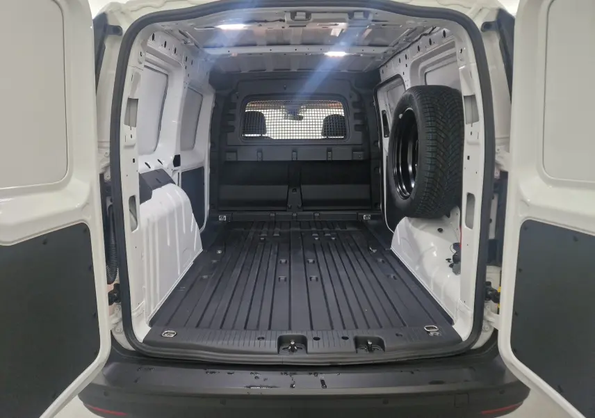 Vue arrière du Volkswagen Caddy Maxi blanc 2025 avec intérieur utilitaire vide et roue de secours fixée à droite.