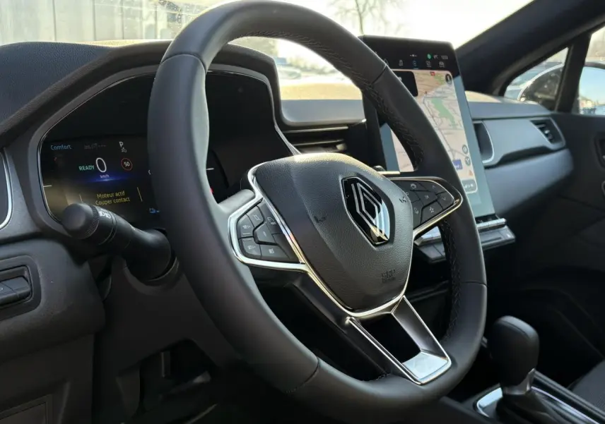 Vue rapprochée du volant noir et du tableau de bord numérique du Renault Captur 2025 avec écran tactile vertical.
