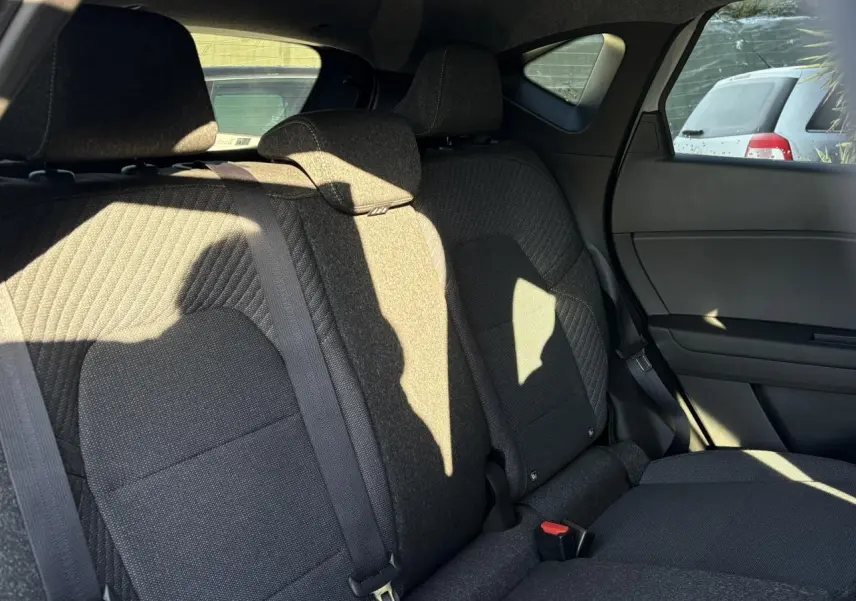 Vue intérieure côté droit des sièges arrière en tissu noir du Renault Captur 2025 hybride, avec ceinture de sécurité visible.