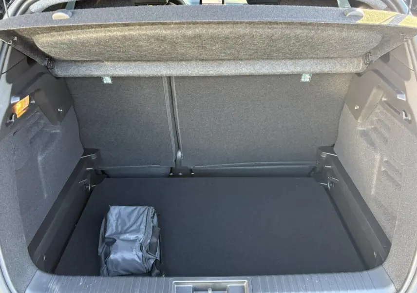 Vue intérieure du coffre ouvert du Renault Captur gris Rafale, montrant un rangement avec sac noir posé.