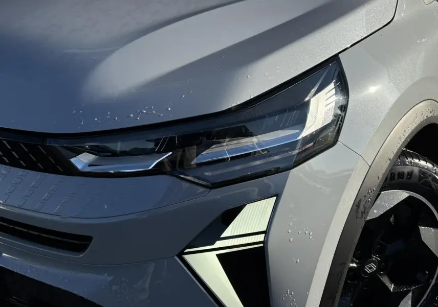 Gros plan sur l'avant droit du Renault Captur gris Rafale, mettant en valeur le phare LED et la jante aluminium noire.