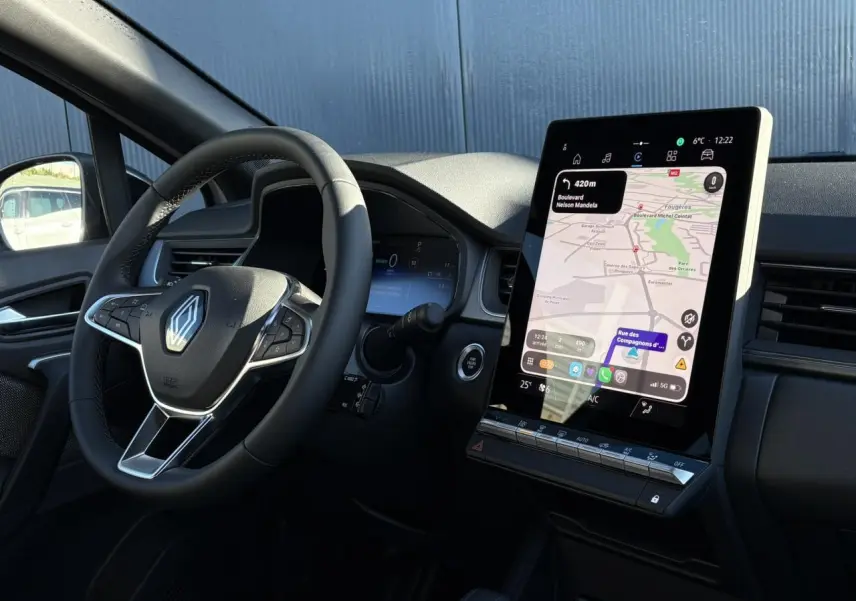 Vue intérieure côté conducteur du Renault Captur 2025 avec volant noir et écran tactile vertical 10,4 pouces affichant la navigation.