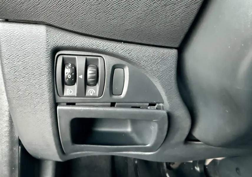 Gros plan sur les commandes d’éclairage et réglage du tableau de bord côté gauche d’une Renault Twingo II grise.