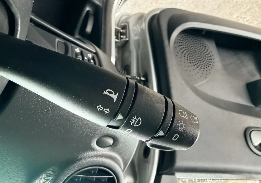 Gros plan sur la commande des phares et clignotants à gauche du volant dans une Renault Twingo II gris de 2009.