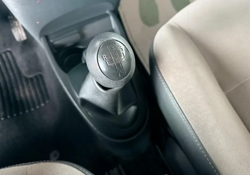 Gros plan sur le levier de vitesses manuel noir et siège tissu gris clair à l'intérieur d'une Renault Twingo II.