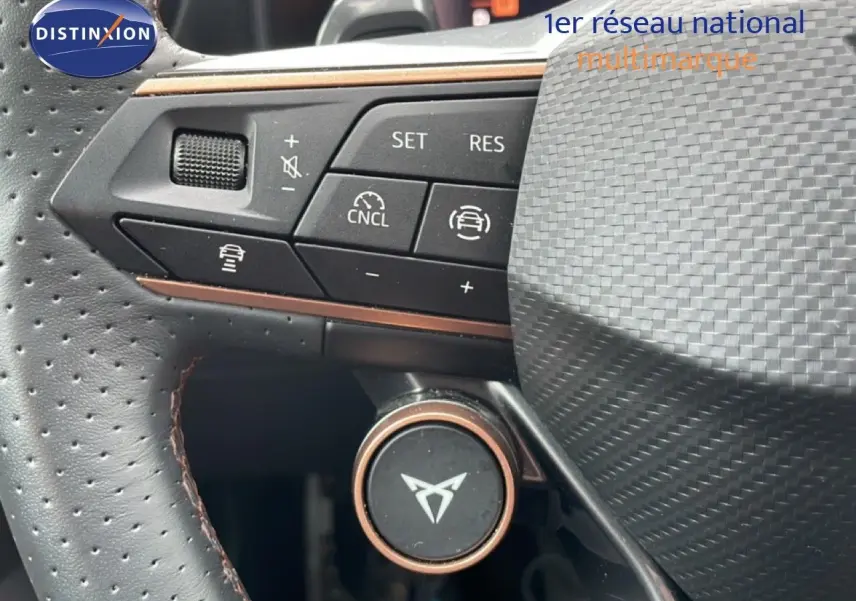 Gros plan sur le volant perforé gris avec commandes intégrées et logo CUPRA au centre, soulignant la finition soignée.