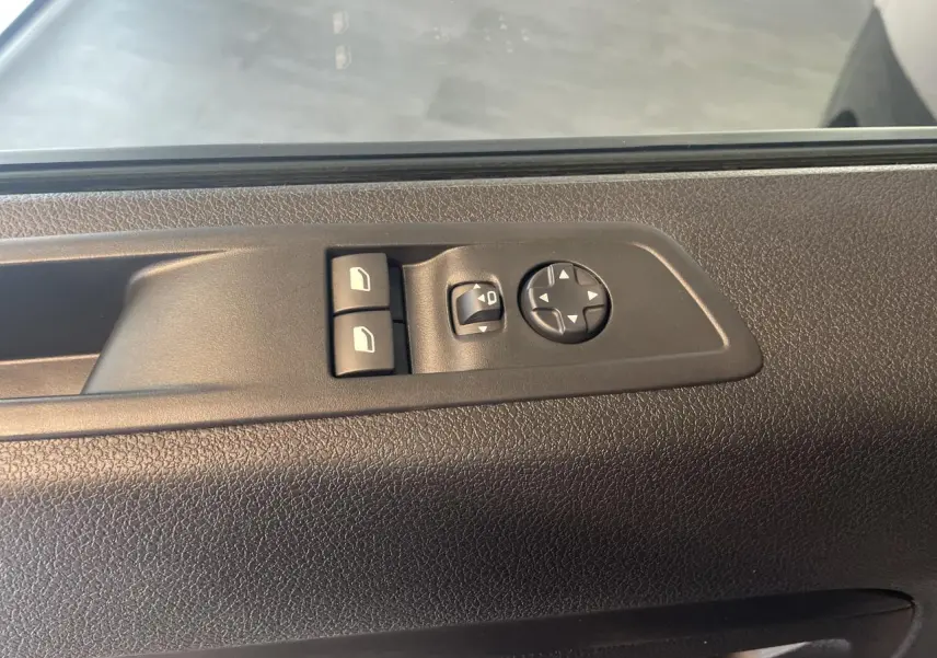 Gros plan sur les commandes de lève-vitres et réglage des rétroviseurs sur la porte côté conducteur d'un Opel Vivaro noir carbone.