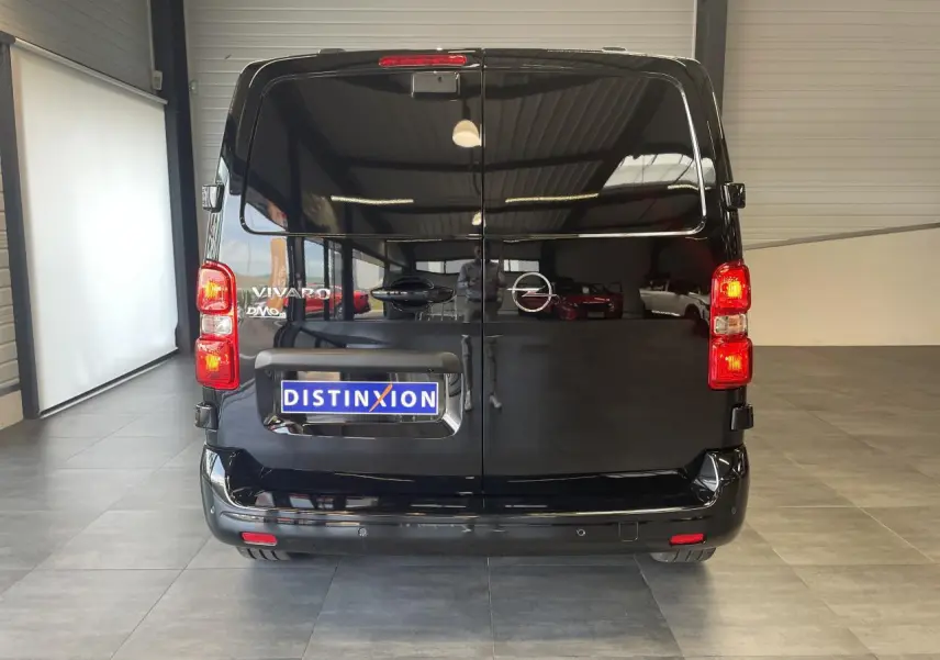 Vue arrière d'un Opel Vivaro noir carbone avec portes battantes et feux arrière allumés en intérieur showroom.
