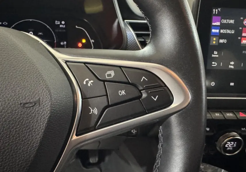 Gros plan sur les commandes au volant en cuir noir du Renault Arkana Business E-TECH 145, avec écran tactile visible à droite.