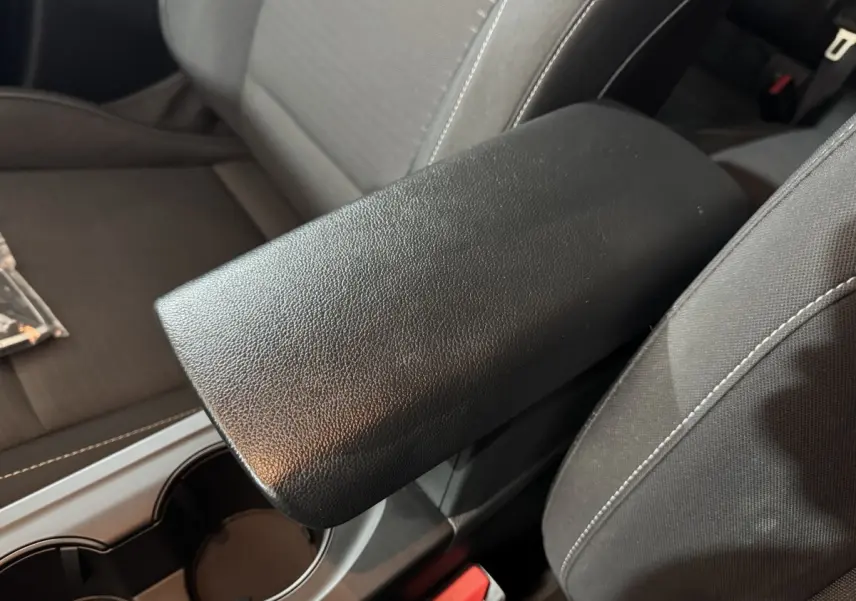 Accoudoir central noir en cuir synthétique entre les sièges avant gris foncé du Renault Arkana Business E-TECH 145.