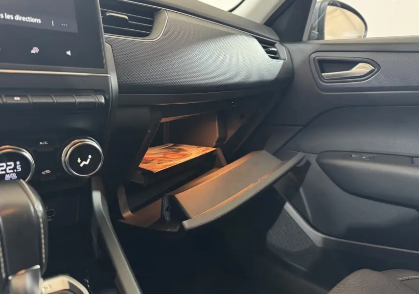 Vue intérieure côté passager du tableau de bord gris foncé et boîte à gants ouverte du Renault Arkana Business E-TECH 145.