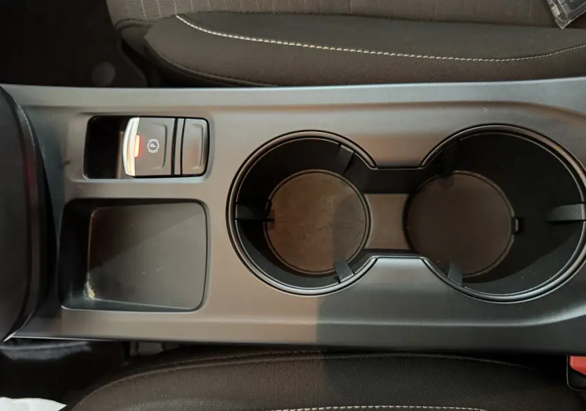 Vue rapprochée de la console centrale noire avec porte-gobelets et bouton frein à main électrique allumé sur Renault Arkana Business E-TECH 2022.