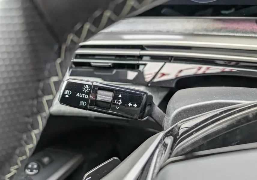 Gros plan sur la commande des feux et clignotants à gauche du volant du Peugeot 3008 GT bleu métallisé 2025.