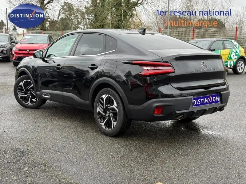 Vue 3/4 arrière droite d'une Citroën C4 X 2024 noire Perla Nera avec feux arrière LED et jantes distinctives.