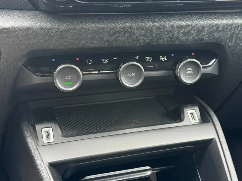 Gros plan sur la console centrale du Citroën C4 X 2024, montrant les commandes de climatisation et un rangement noir.