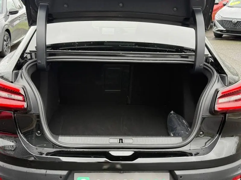 Coffre ouvert vu de l'arrière d'une Citroën C4 X 2024 noire Perla Nera avec feux arrière LED distinctifs.