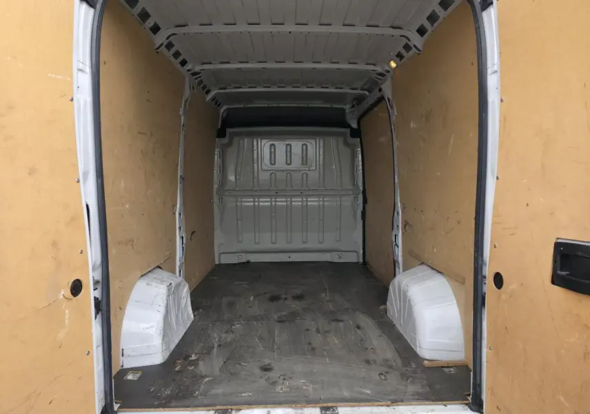 Vue intérieure arrière du fourgon Opel Movano blanc, montrant l'espace de chargement vide avec parois en bois.