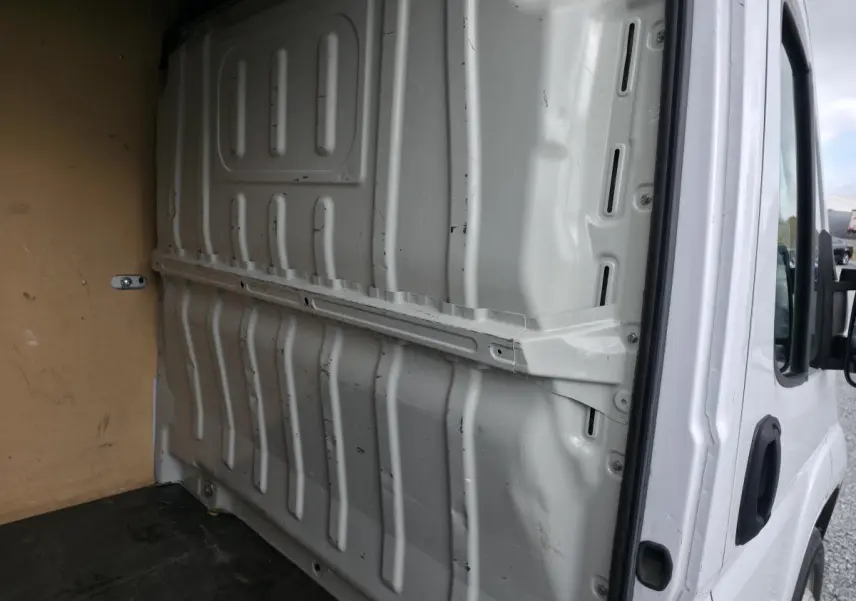 Vue intérieure du fourgon Opel Movano blanc, montrant la cloison pleine tôlée séparant la cabine et l'espace de chargement.