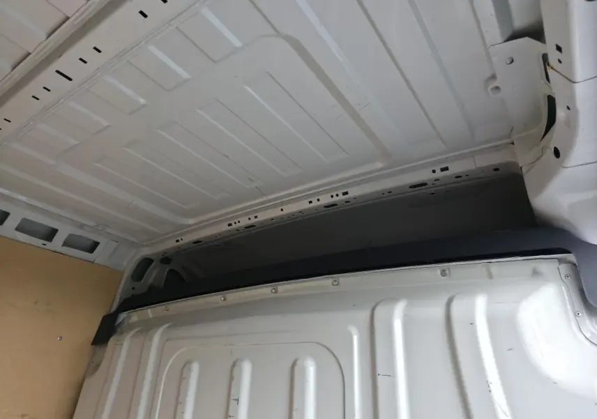 Vue intérieure du fourgon Opel Movano blanc montrant la cloison pleine tôlée de séparation et le plafond métallique.