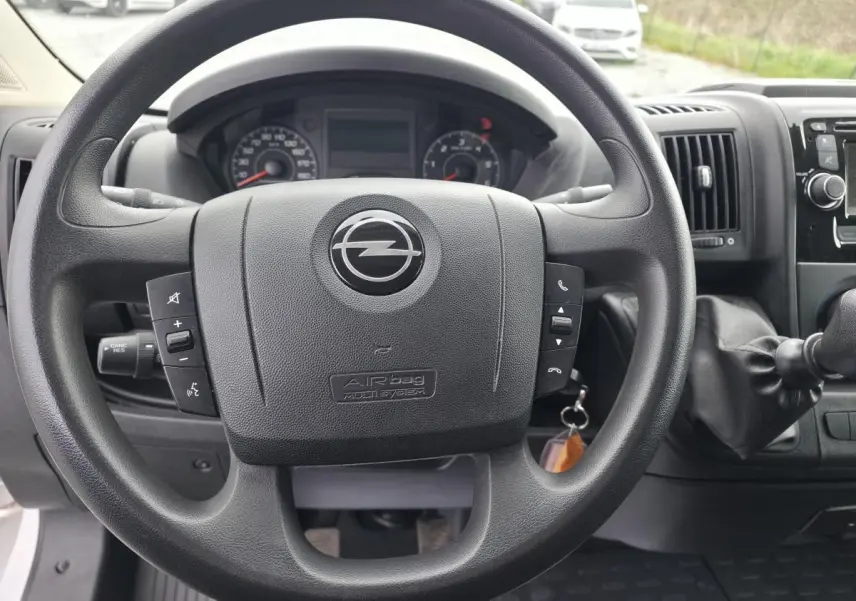 Vue rapprochée du volant Opel Movano Fourgon 2022 avec commandes intégrées et levier de vitesses manuel.