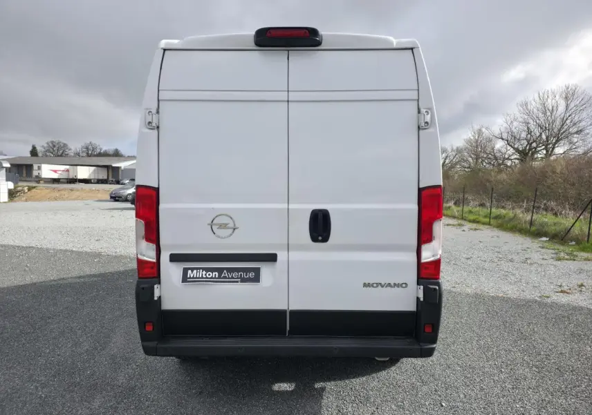 Vue arrière d'un fourgon Opel Movano blanc avec portes battantes et feux rouges verticaux.