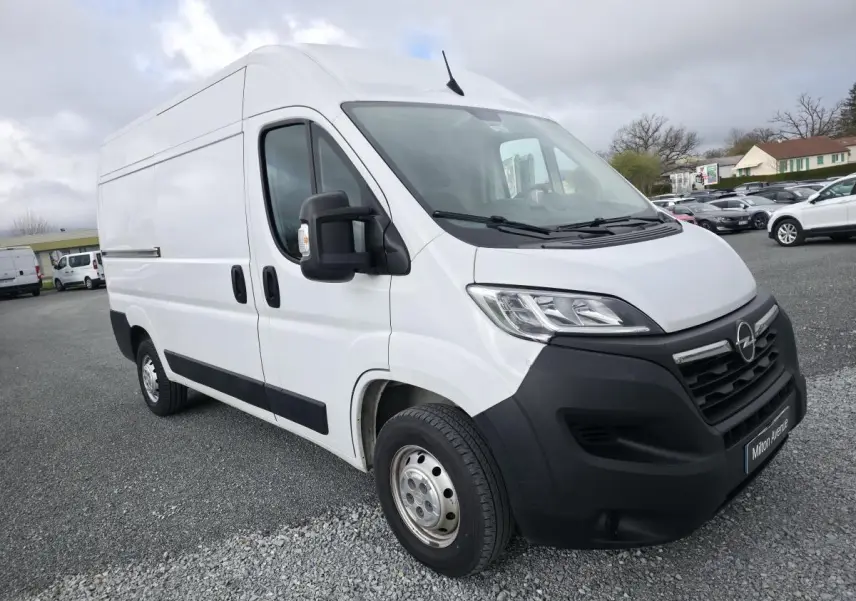 Vue 3/4 avant gauche d’un Opel Movano Fourgon blanc avec calandre noire et jantes tôles grises sur parking.