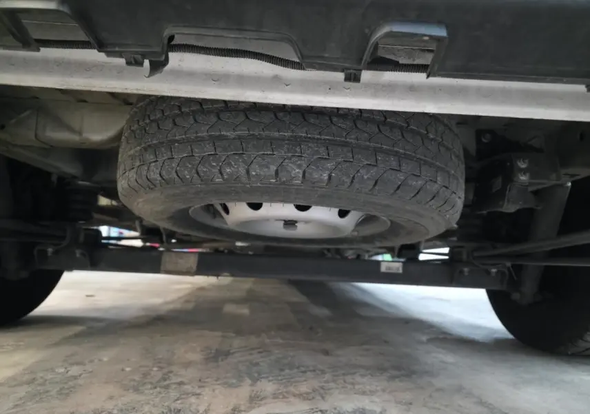 Vue en contre-plongée sous un Opel Movano blanc montrant la roue de secours montée sous le châssis.