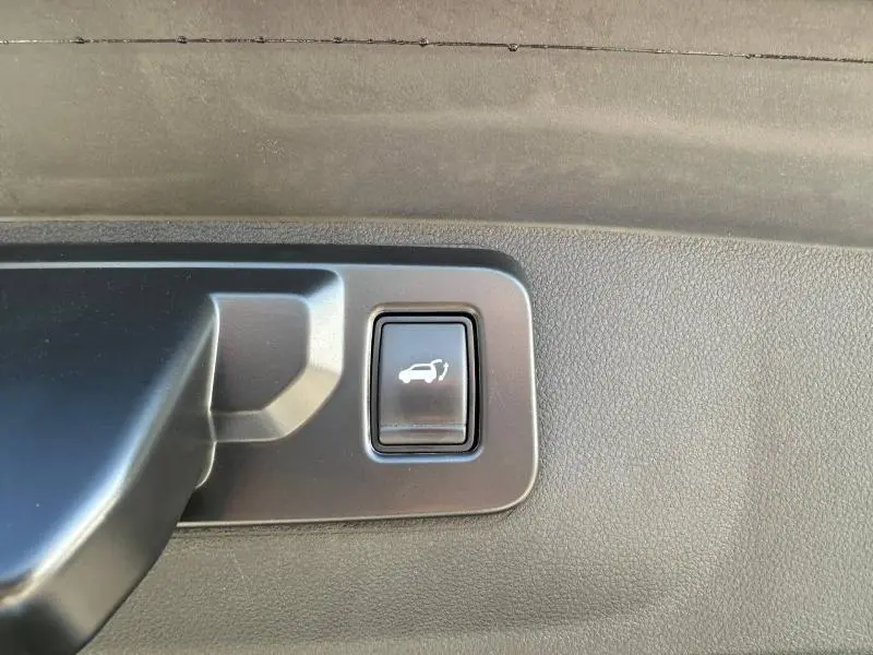 Bouton d'ouverture électrique du coffre sur panneau intérieur noir du Renault Rafale 1.2 E-Tech bleu sommet.